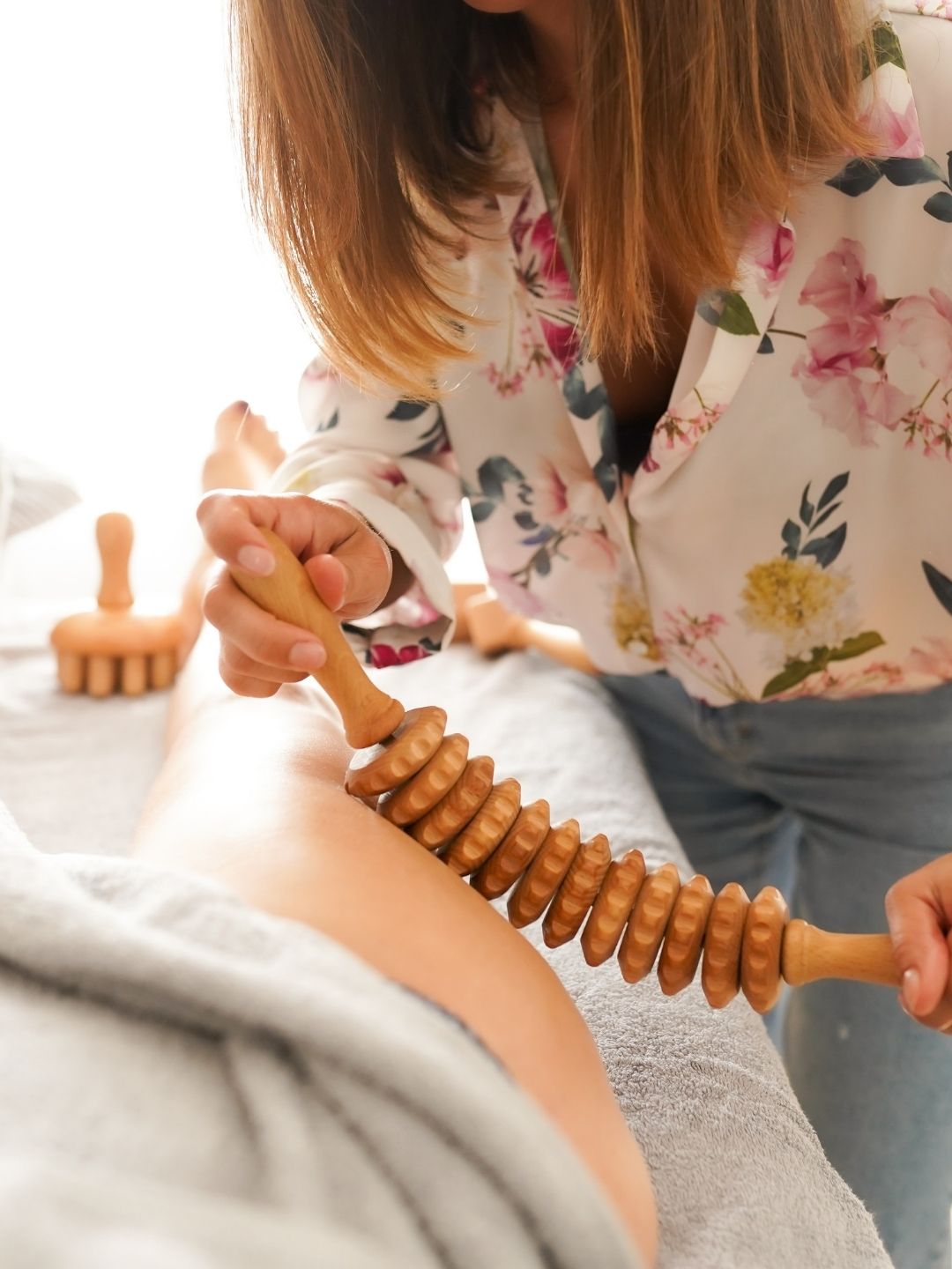 Massage de la cuisse au rouleau de madérothérapie en bois